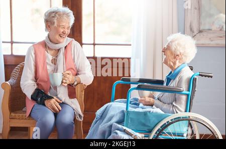 Disabled senior woman, friends and coffee with smile, funny conversation or talking with laugh, wheelchair or happy. Elderly women, drinking tea ort Stock Photo