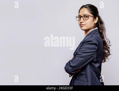 Confident Young Indian Girl Model Posing with Folded Hands in Clean Copyspace, Perfect for Brand Endorsements and Corporate Advertising Campaigns Stock Photo