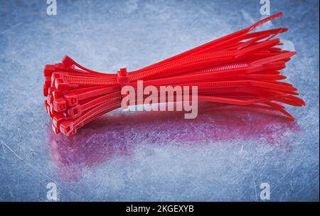 Red plastic self-locking cable ties on metallic background construction concept. Stock Photo