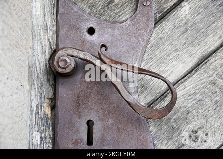 Old forged metal door handle on a wooden door of a historic castle. Stock Photo