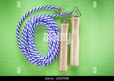 Rolled skipping rope on green background fitness concept. Stock Photo