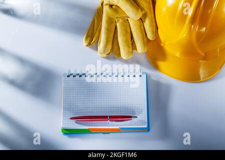 Safety gloves hard hat notepad pen on white background. Stock Photo