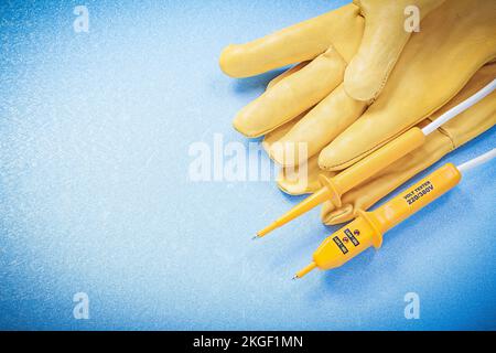 Safety gloves electric tester on blue background electricity concept. Stock Photo