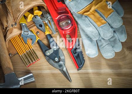 Tool belt with tooling construction level protective gloves on wooden board. Stock Photo