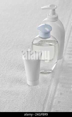 two bottles and tube on white towel Stock Photo