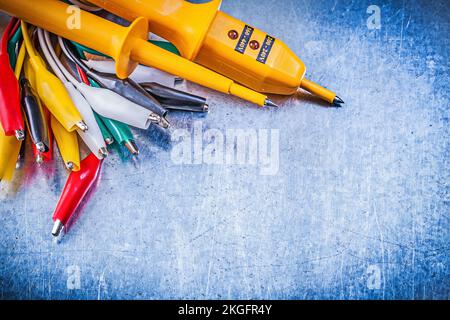 Yellow electrical tester crocodile cables set on metallic background electricity concept. Stock Photo