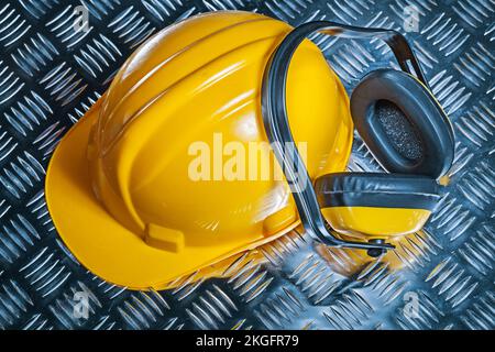 yellow helmet and  earphones on corrugated sheet of metal Stock Photo