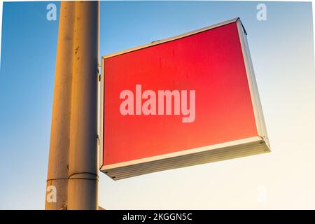 Blank red plastic signboard on post. Empty mounted sign plate mock up. Clear outdoor plexiglass signage for hotel or store info mockup template. Stock Photo