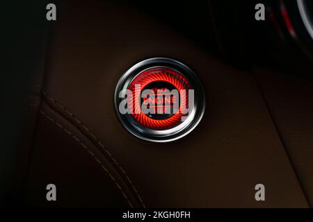 A Mercedes AMG Engine Start Stop button turned on, red, in brown leather with chrome border Stock Photo