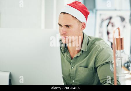 Businessman, computer and working with christmas hat in office at digital marketing job on internet. Man, holiday and work on pc, web or online with Stock Photo