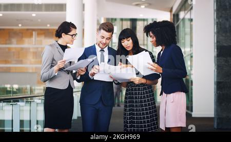 Business people team reading paperwork, documents and planning strategy, financial information or company analytics in modern office. Diversity Stock Photo