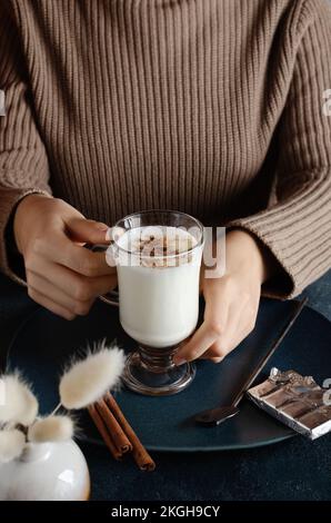 Young woomen holding a glass with homemade milk dessert with spices,cinnamon and dark chocolate flakes. Stock Photo