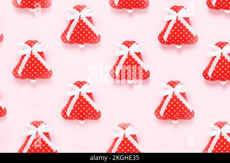 Handmade Christmas red fabric bells of  with white ribbon on pink background. Stock Photo