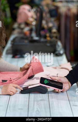 Counter with a customer paying with smartphone in a clothing shop Stock Photo