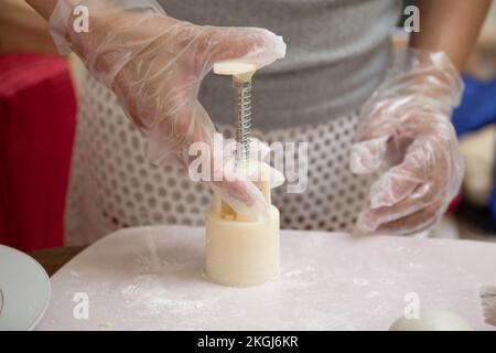 A Female hands with transparent gloves Making Mooncake in a plastic mould Stock Photo