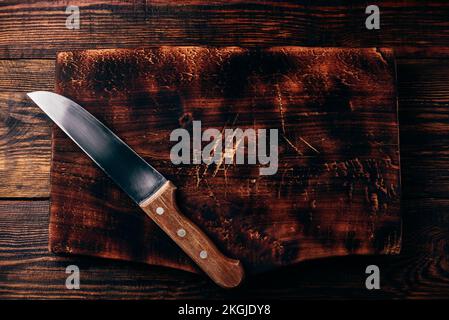 Knife over rustic wooden cutting board Stock Photo