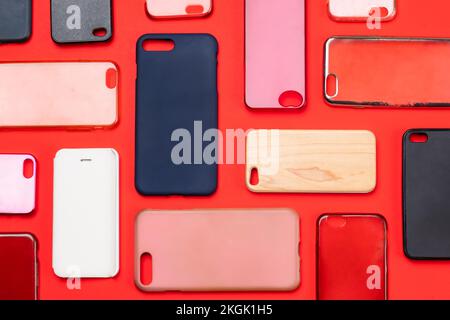 Pile of multicolored plastic back covers for mobile phone. Choice of smart phone protector accessories on red background. A lot of silicone phone back Stock Photo