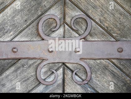 Metal ornament on an old weathered wooden door. Antique element as background image. Stock Photo