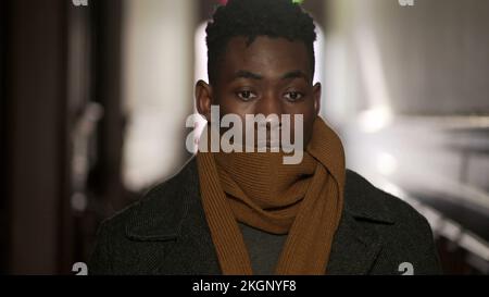 Young black man wearing scarf winter clothing walking in corridor leaving home Stock Photo