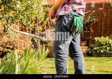 Close-up of man holding watering can in garden Stock Photo