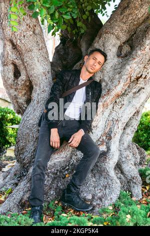 Man sitting on tree trunk at park Stock Photo