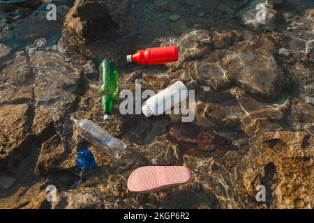 Empty plastic bottles and slippers floating on water Stock Photo