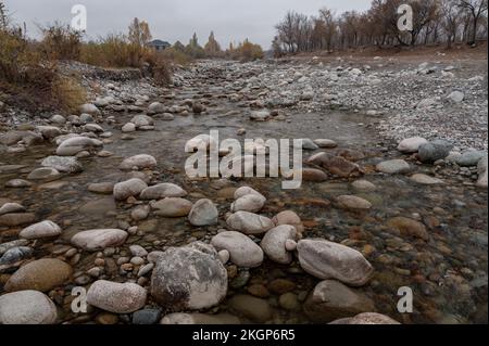 Slow and not deep mountain river with rounded stones Stock Photo