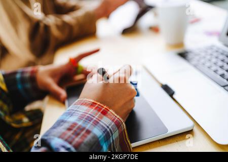 Hands of illustrator using graphics tablet by laptop at desk Stock Photo