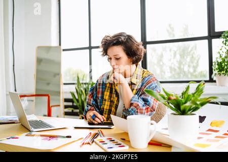 Illustrator with graphics tablet working at desk Stock Photo