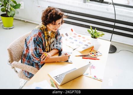 Illustrator with graphics tablet working on laptop at desk Stock Photo