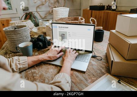 Hands of craftswoman using laptop on workbench Stock Photo