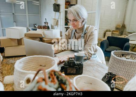 Craftswoman using laptop on workbench in workshop Stock Photo