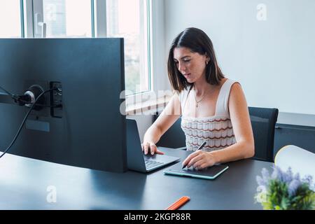 Smiling young graphic designer using laptop in office Stock Photo