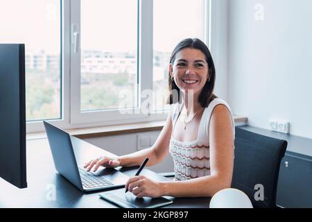 Happy young graphic designer using laptop in office Stock Photo