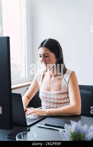 Smiling customer service representative with headset using laptop in office Stock Photo