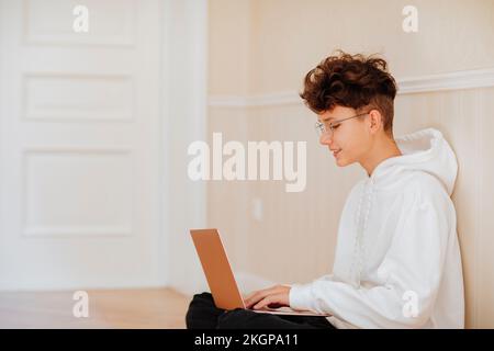 Smiling boy using laptop at home by wall Stock Photo
