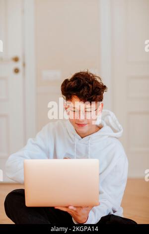 Smiling boy using laptop at home Stock Photo