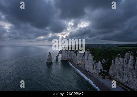France, Normandy, Etretat, Falaise dAval cliffs and Aiguille dEtretat sea stack at cloudy dusk Stock Photo