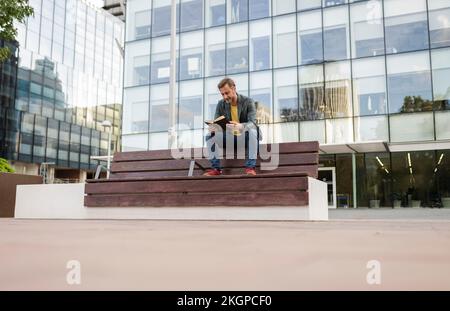 Man sitting on bench and reading book Stock Photo