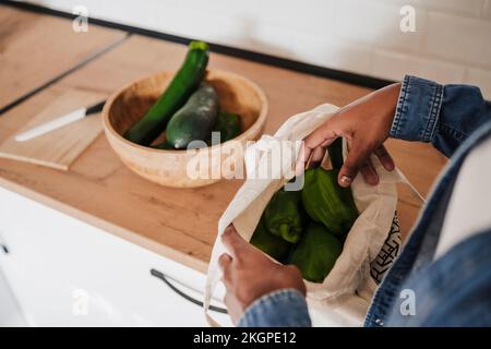 Hands of woman removing vegetables from bag at kitchen counter Stock Photo