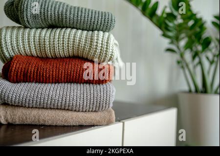 Knitted warm sweaters on dresser at home Stock Photo