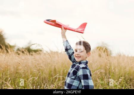Smiling cute boy playing with model airplane in field Stock Photo