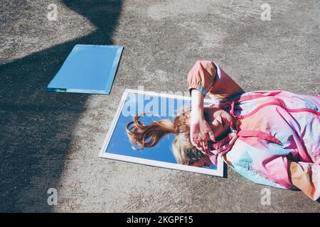 Woman shielding eyes from sunlight lying down on mirror Stock Photo