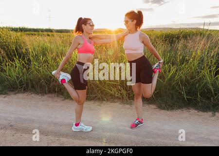 Smiling woman with instructor doing stretching exercise on sunny day Stock Photo