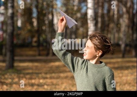 Boy playing with paper airplane in park Stock Photo