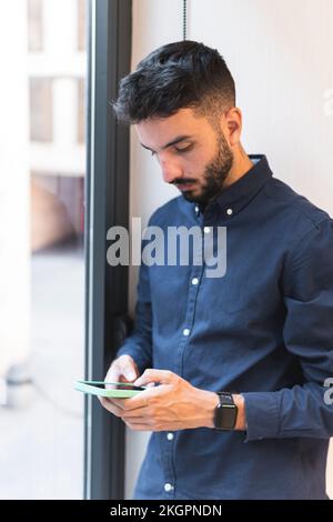 Young businessman using smart phone by window Stock Photo