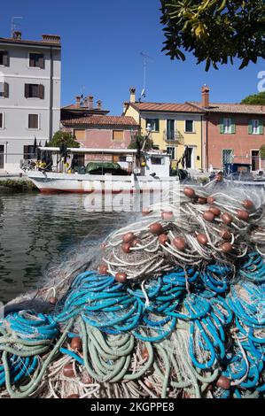 Italy, Friuli Venezia Giulia, Grado, Fishing nets lying in front of old town canal Stock Photo