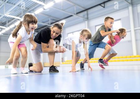 Teacher cheering students at race in school sports court Stock Photo