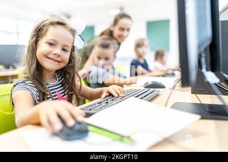 Smiling student sitting in computer class at school Stock Photo
