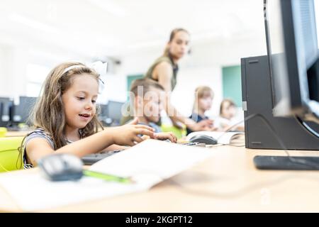 Girl typing on keyboard sitting in computer class at school Stock Photo
